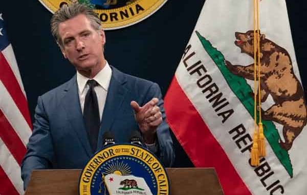 Gavin Newsom next to a California state flag